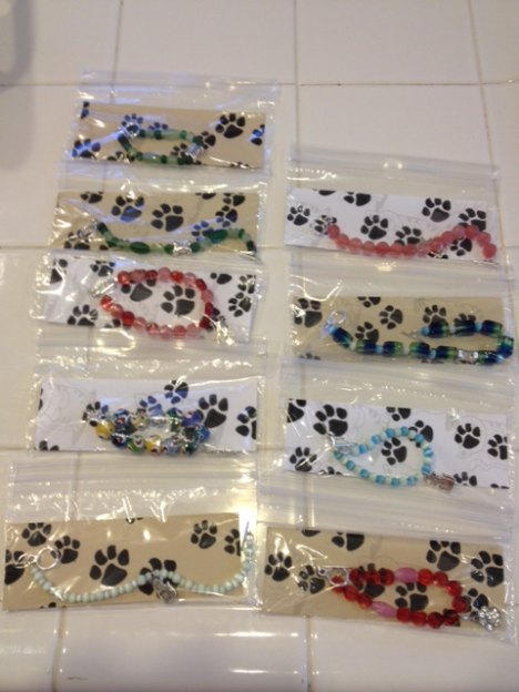 Bracelets have colorful beads and a paw or cat charm.